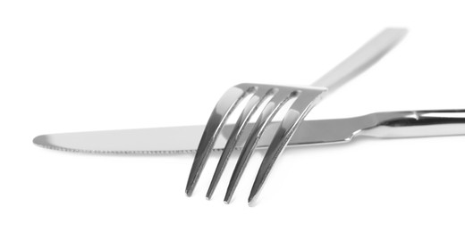 Photo of New shiny fork and knife on white background, closeup