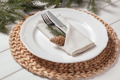 Photo of Stylish festive place setting with plate, cutlery and fir branches on white wooden table, closeup