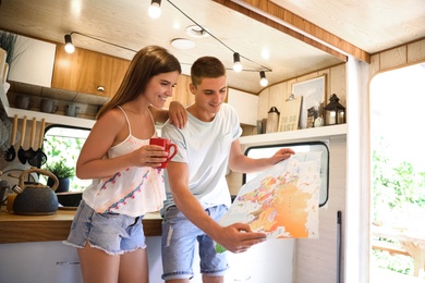 Young travelers with world map planning trip in motorhome