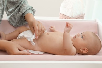 Mother changing her baby's diaper on table at home