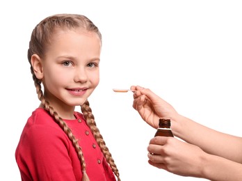 Photo of Mother giving syrup to her daughter from dosing spoon against white background