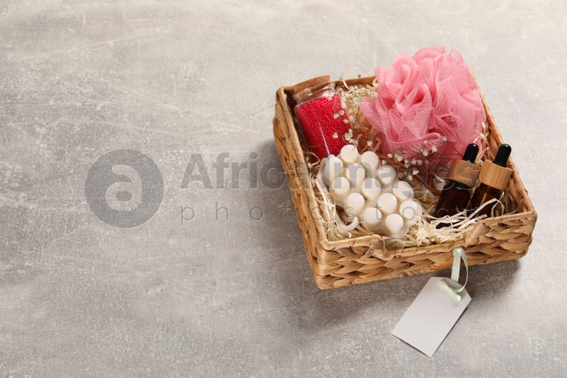 Spa gift set of different luxury products in wicker basket on grey table, space for text