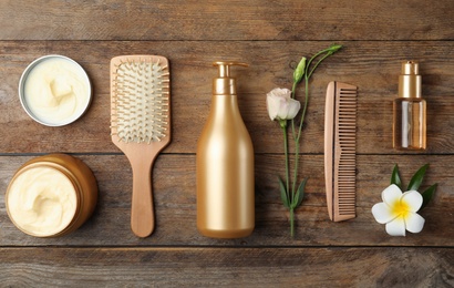 Flat lay composition with hair cosmetic products on wooden table