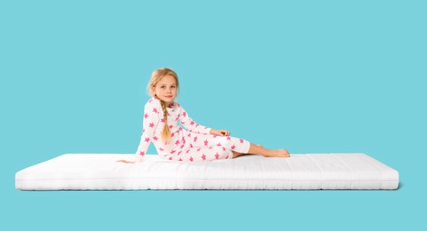 Photo of Little girl on mattress against light blue background