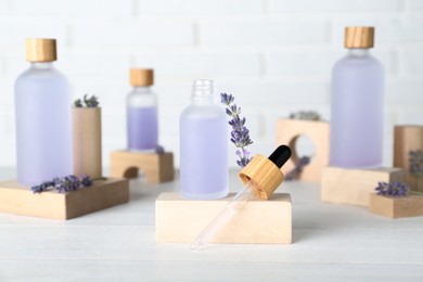 Bottles of lavender essential oil and flowers on wooden table
