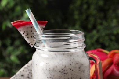 Delicious pitahaya smoothie in mason jar and fresh fruits on blurred background, closeup