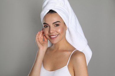 Photo of Beautiful young woman with towel on head against grey background