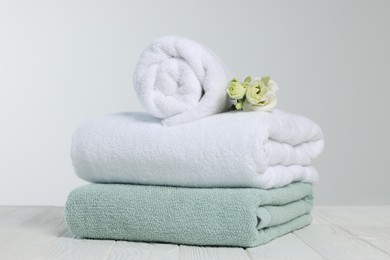 Soft towels with flowers on wooden table against white background
