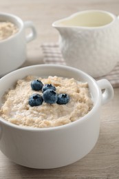 Tasty oatmeal porridge with blueberries in bowl served on wooden table