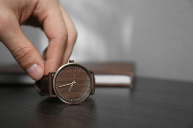 Man putting luxury wrist watch on table, closeup. Space for text