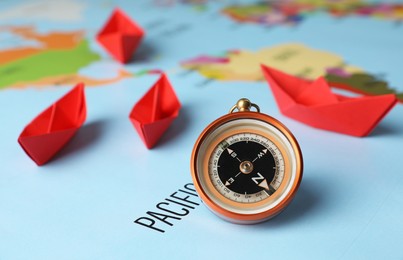 Bright paper boats and compass on world map