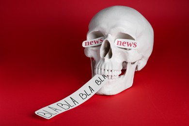 Photo of Information warfare concept. Saying useless nonsense as result of media propaganda influence. Human skull with paper cards on red background