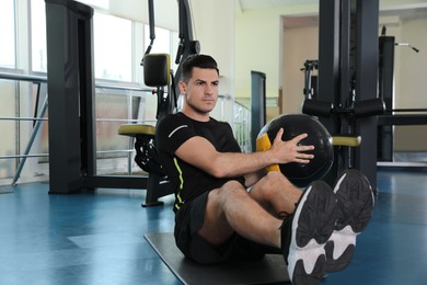 Athletic man exercising with medicine ball in modern gym