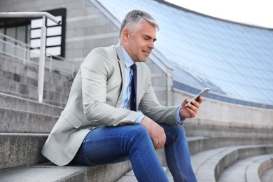 Portrait of handsome businessman with mobile phone in city