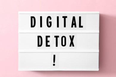 Lightbox with phrase DIGITAL DETOX on pink background, top view