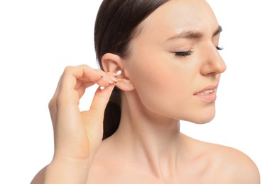 Young woman cleaning ear with cotton swab on white background, closeup