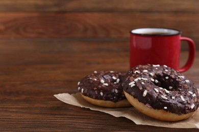 Two frosted donuts with sprinkles and cup of coffee on wooden table, space for text