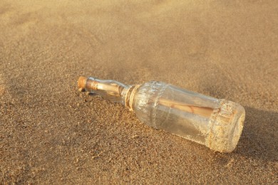 SOS message in glass bottle on sand, closeup