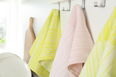 Different kitchen towels hanging on hook rack indoors, closeup