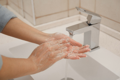 Woman washing hands with antiseptic soap in bathroom, closeup. Virus prevention