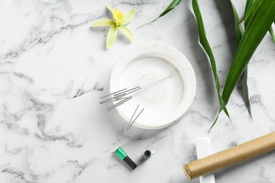Flat lay composition with acupuncture needles on white marble table. Space for text