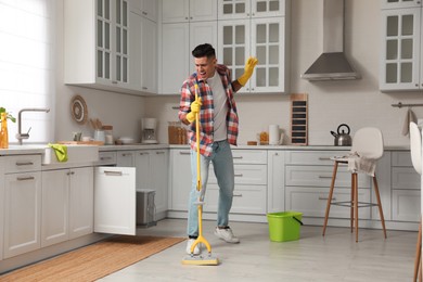 Man with mop singing while cleaning at home