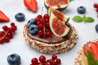 Tasty crispbreads with chocolate, figs and berries on light table, closeup
