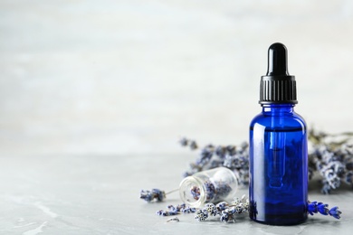 Photo of Bottle of natural essential oil and lavender flowers on grey marble background. Space for text