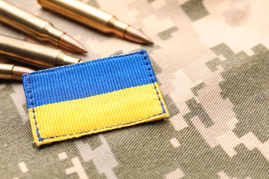 Military patch and bullets on pixel Ukrainian camouflage, closeup