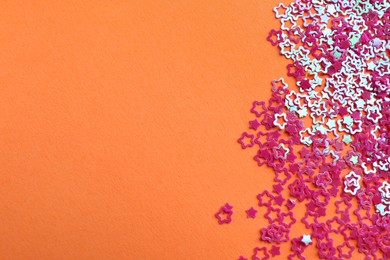 Photo of Shiny bright star shaped glitter on coral background. Space for text