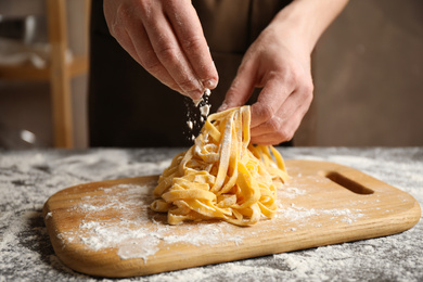 Photo of Woman preparing pasta at table, closeup view