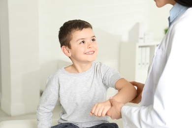 Professional orthopedist examining little patient's arm  in clinic