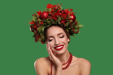 Photo of Beautiful young woman wearing Christmas wreath on green background