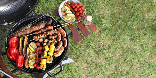 Photo of Tasty meat and vegetables on barbecue grill outdoors, top view
