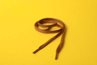 Long brown shoe lace on yellow background