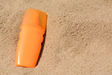 Bottle with sun protection spray on sandy beach, above view. Space for text