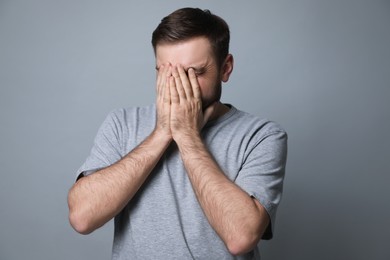 Young man feeling fear on grey background