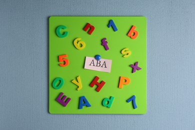 Magnetic board with abbreviation ABA (Applied behavior analysis), colorful letters and numbers on light grey wall