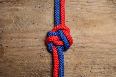 Colorful ropes tied together on wooden background, top view. Unity concept