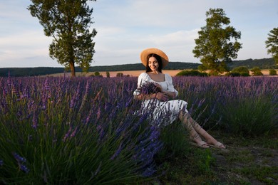 Photo of Beautiful young woman sitting in lavender field at sunset