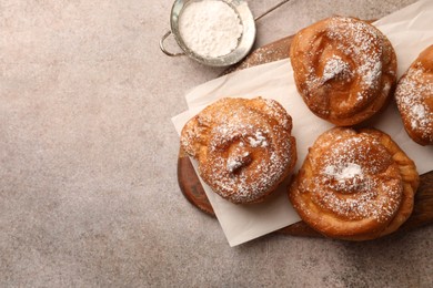 Photo of Delicious profiteroles with powdered sugar on grey table, flat lay. Space for text