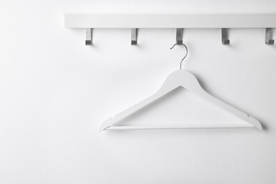 Rack with empty clothes hanger on white wall