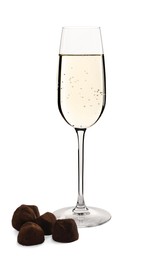 Photo of Glass of delicious sparkling wine and chocolate truffles isolated on white