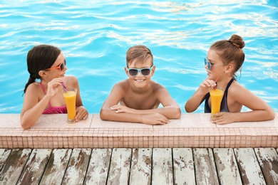 Happy children with drinks in swimming pool