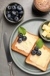 Delicious toasts served with butter, blueberries and coffee on grey wooden table, flat lay