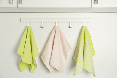 Different kitchen towels hanging on hook rack indoors
