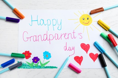 Beautiful drawing with phrase Happy Grandparents Day on white wooden table, flat lay
