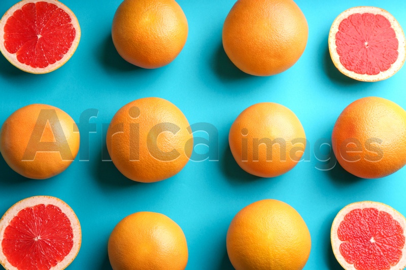 Cut and whole ripe grapefruits on blue background, flat lay