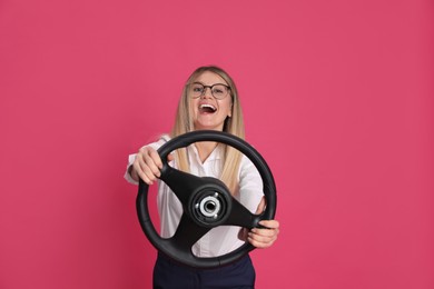 Emotional young woman with steering wheel on crimson background