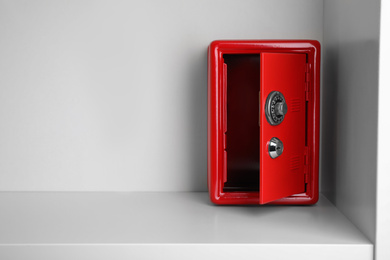 Red steel safe with mechanical combination lock on shelf. Space for text